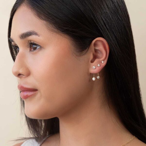 Model Wears Diamond Mara 0.10Ct 0.16Ct 0.25Ct 3 Prong Studs Stacked Jen Round Bezel Drop Earring Enhancer Yellow Gold Cropped