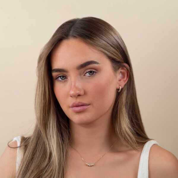 Model Wears Lab Grown Diamond Kira Graduating Bezel Huggie Earrings August Round Bezel Slider Yellow Gold Pendant