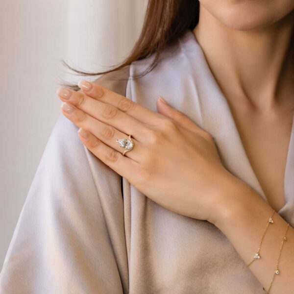 Model Wears Jessica Pear Moissanite Under Rail Curved Hammer Set Band Yellow Gold Ring